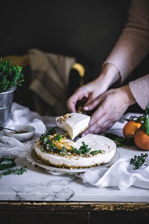 Cook cutting tangerine cake and taking piece