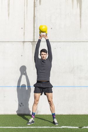 Man training with kettlebell on lawn