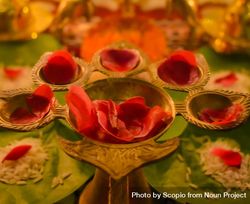 Rose petals on golden panch aarti on a table in close-up 0LJAg4