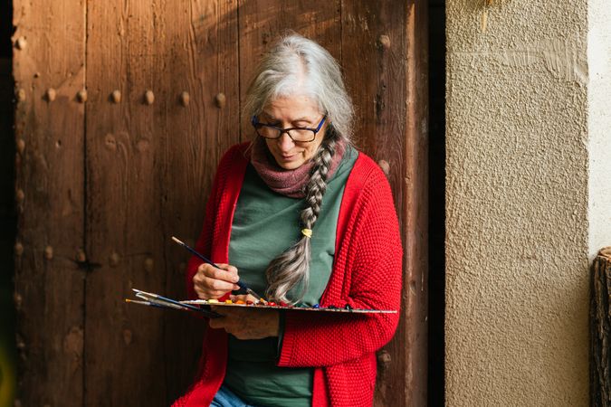 Cheerful painter with paint palette looking at camera