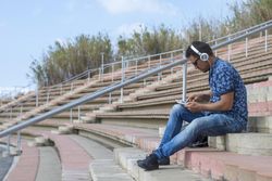 Male sitting on stairs outside and reading