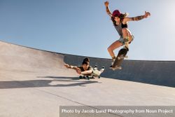 Woman doing an ollie at skate park with friend behind 4mnreb