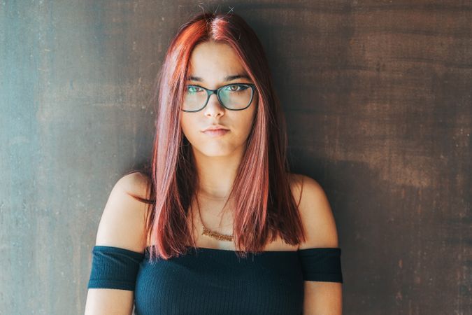Woman in glasses leaning on wall
