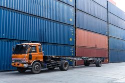 Truck at container warehouse preparing to lift cargo boxes