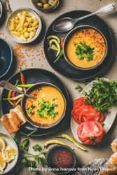 Yellow lentil soup bowls, vegetable garnishes, spices, top view, vertical composition 0JEkdb