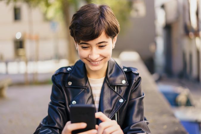 A Cheerful Young Woman Actively Engaged with Her Smartphone While Enjoying the Outdoors