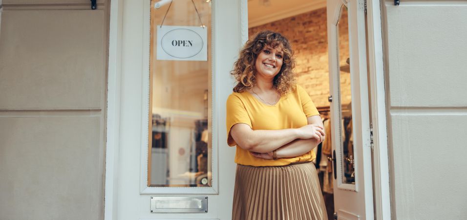 Successful boutique owner standing in front of her shop