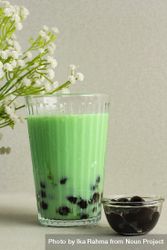 Green boba drink staged next to plant 47gez4