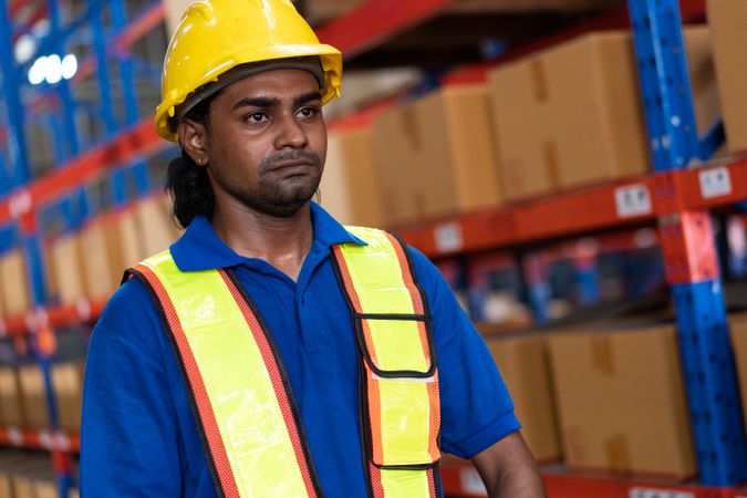 Indian male worker with vision in safety gear in a logistics warehouse.