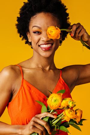 Beautiful Black woman playing with ranunculus flowers