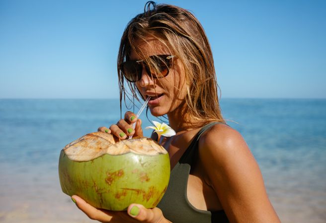 Attractive woman drinking coconut water on the beach