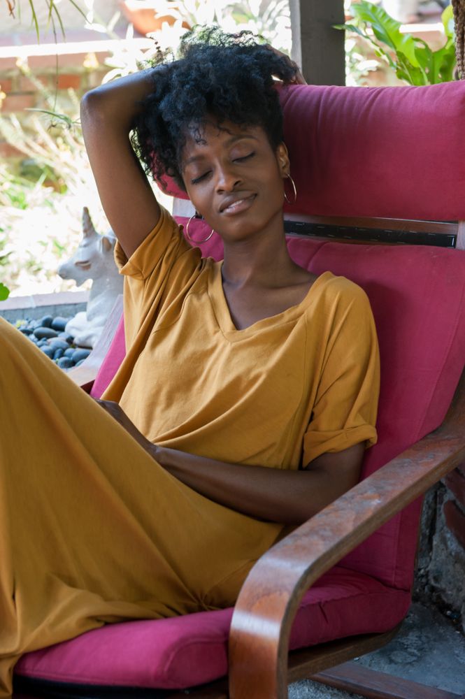Close up portrait of content woman sitting in pink chair with eyes closed
