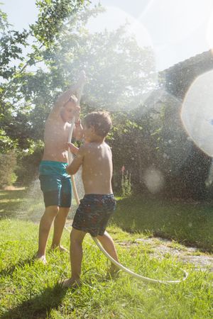 Little kids in swimwear having fun with splashing water