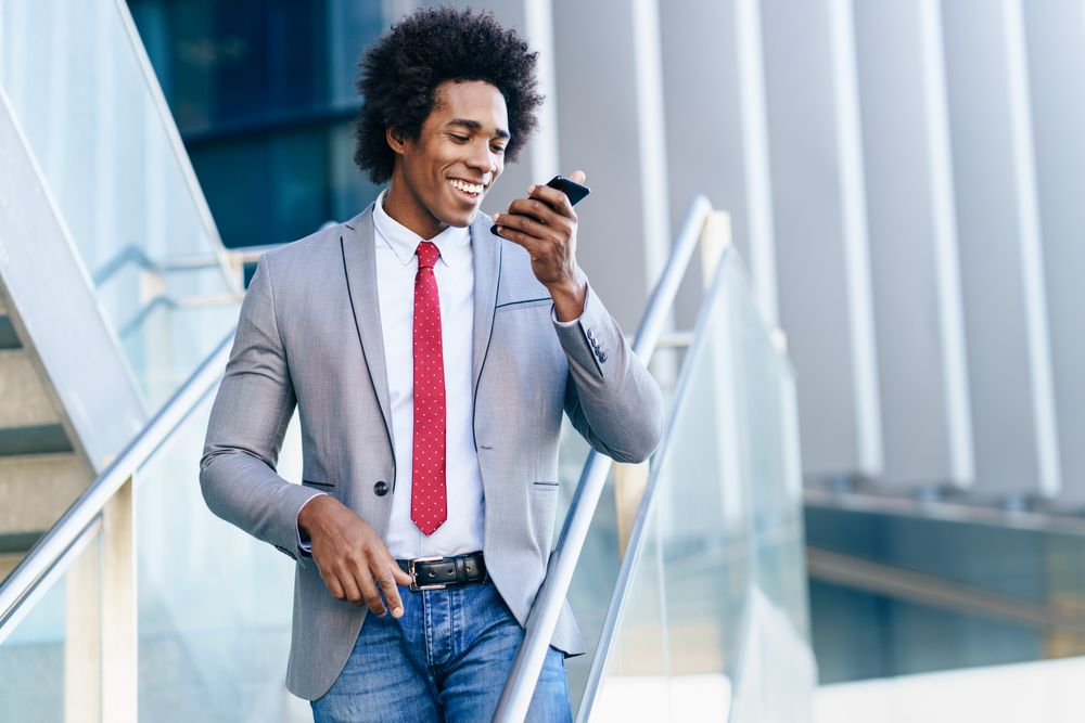 Black man in business casual on stairs speaking on his phone
