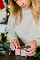 Woman wrapping beautiful Christmas gift at table
