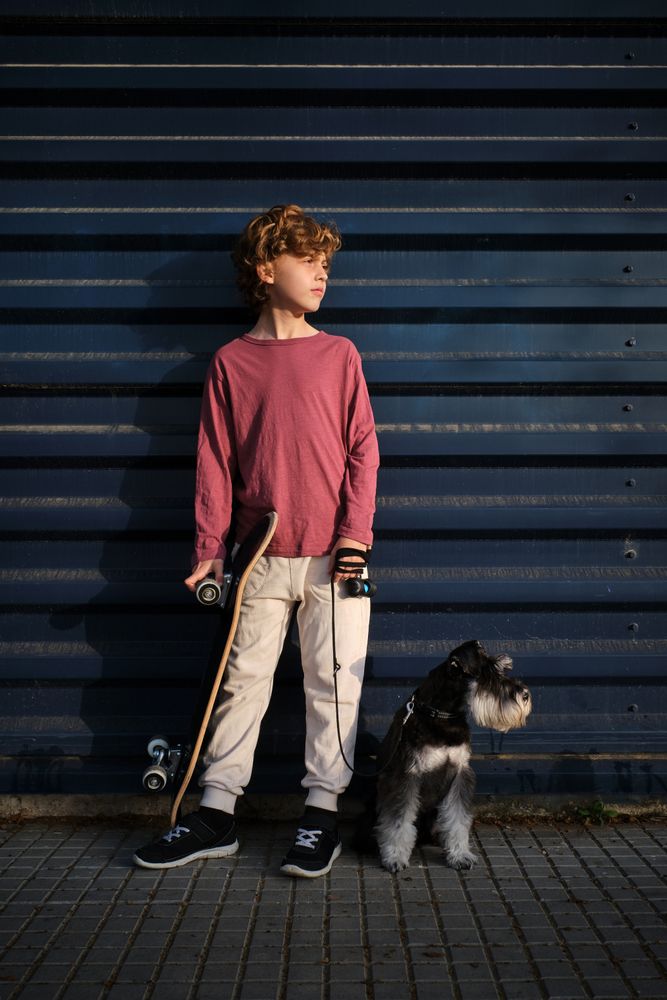 Boy with dog and skateboard on street