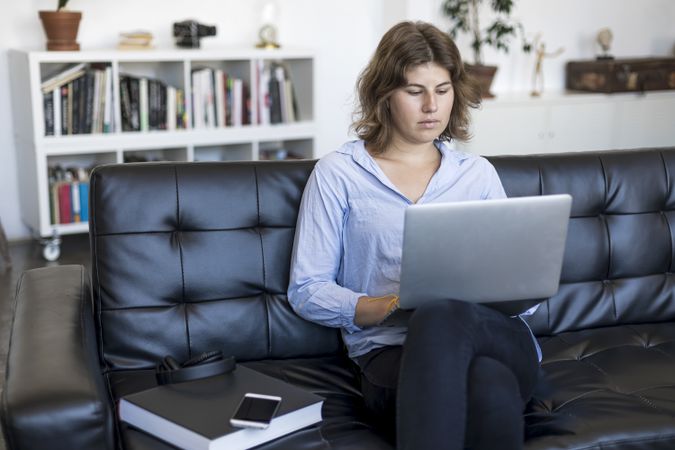 Woman sitting on a sofa at home using a laptop