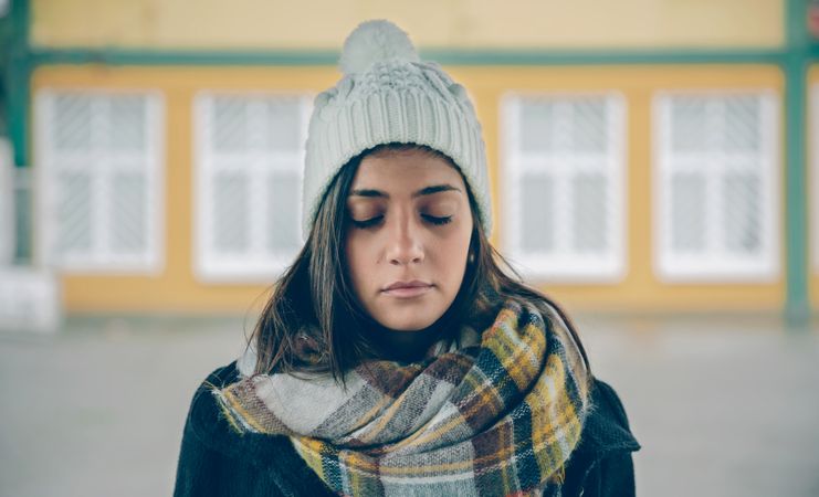 Woman in warm clothes standing outside with eyes closed