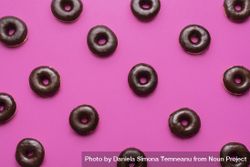 Donuts glazed  with chocolate aligned on a pink background 5XZvob