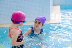 girls in hat smiling and swimming in pool in water park
