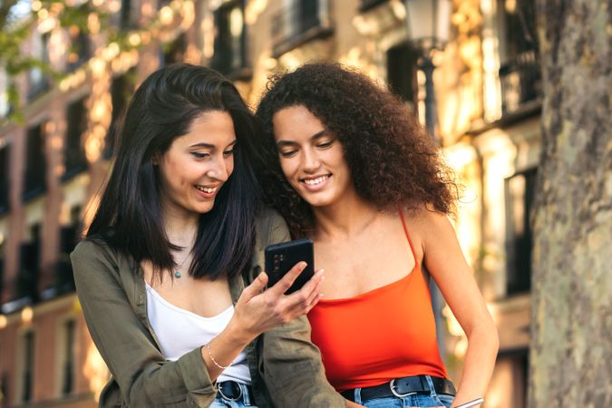 two young women sitting watching something on the mobile