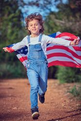 Little boy running with USA flag in nature