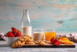 Glasses near fruits and cookies on table near napkin