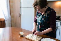 Older woman chopping onion to prepare croquettes at home