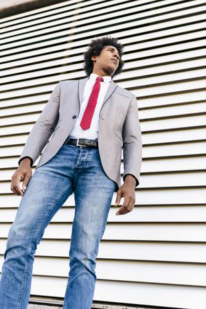 Happy man in jeans and dress shirt with tie standing outside