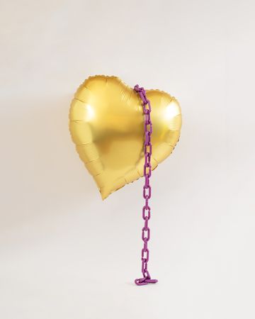 Golden heart balloon in the air with violet purple chains