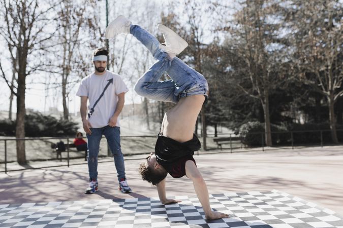 Guy looking at man dancing break dance in park