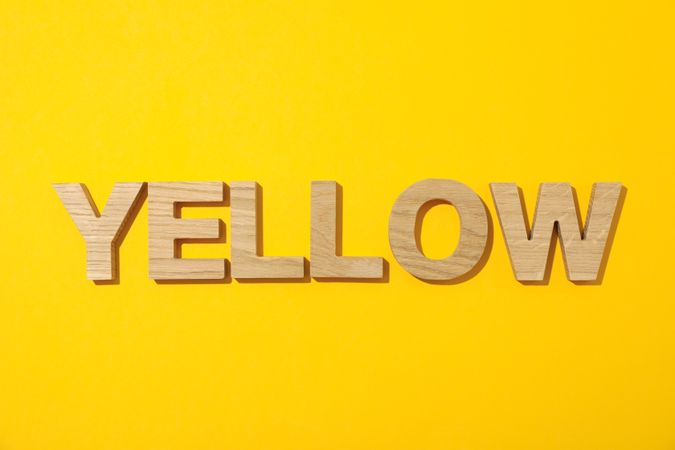 Word Yellow laid out in wooden letters on color background