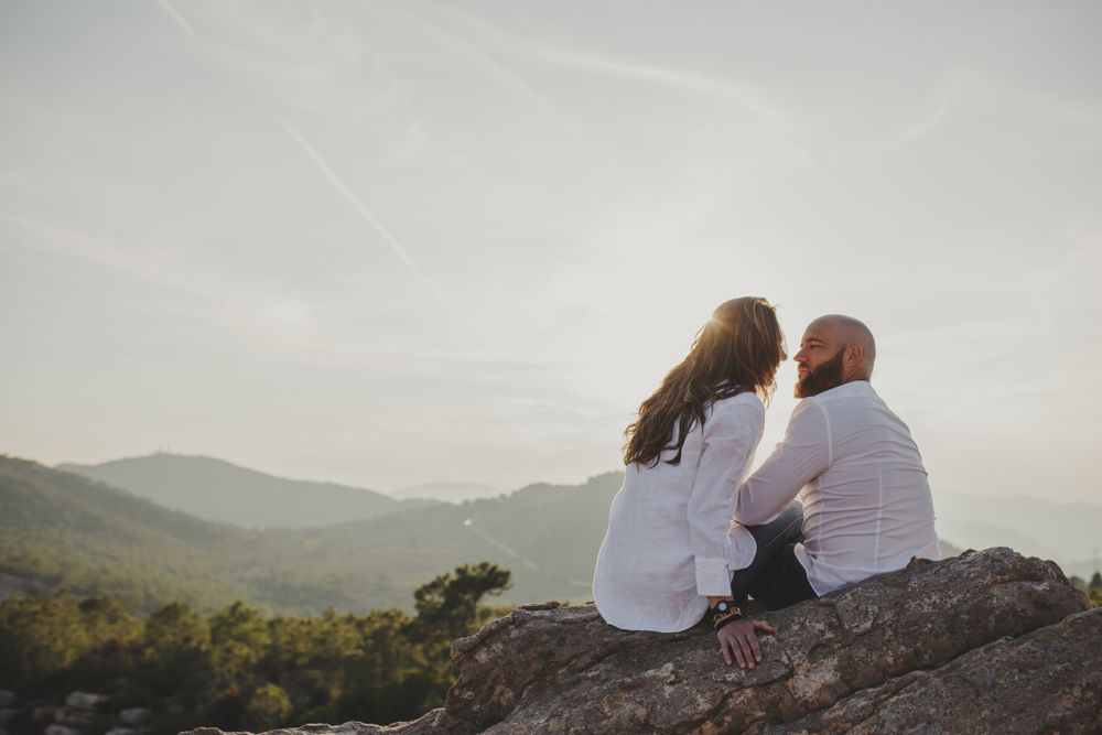 Happy couple sitting at mountain cliff