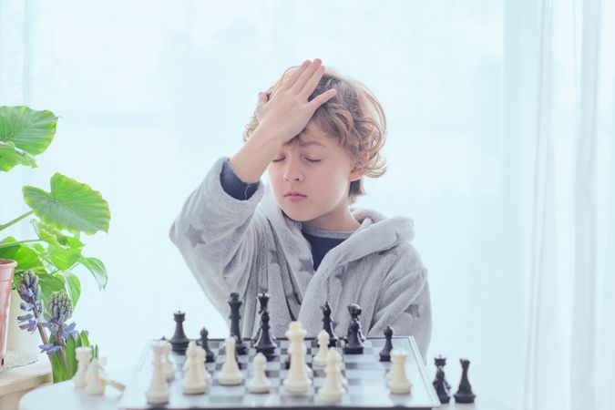 Focused preteen boy thinking over tactic while plying chess