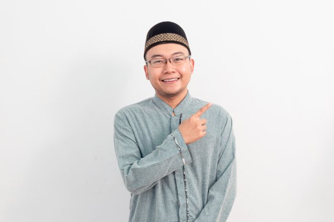 Asian Muslim man smiling doing pointing gesture in Ramadan