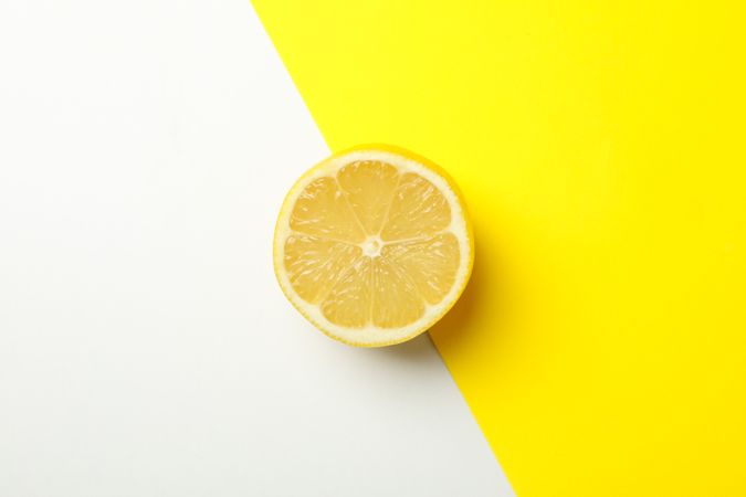 Half of lemon on two tone background, top view. Ripe fruit