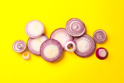 Flat lay composition with red onion rings on color background