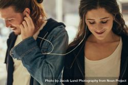 Happy couple listening to music sharing earphones 43R3Z5