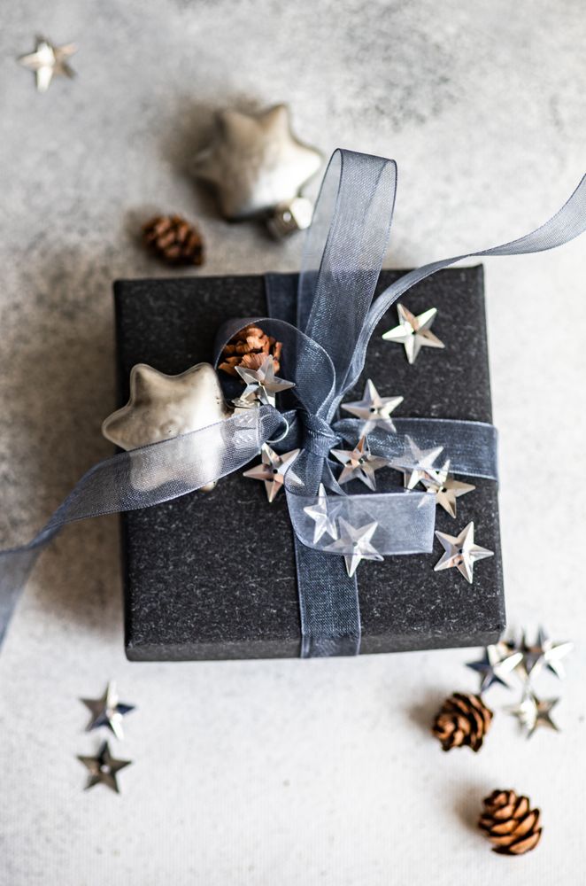 Top view of festive Christmas card concept with blue gift box with star decorations on grey background with copy space