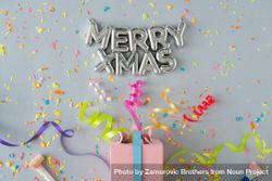 “Merry Xmas” in silver with present with confetti and colorful streamings on grey background 5zaro0