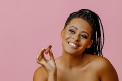 Radiant Black woman holding lip gloss while looking up