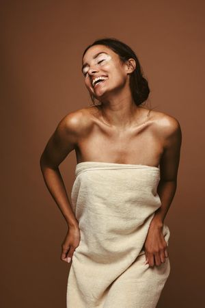 Self-loving woman with skin condition happily dancing in a towel