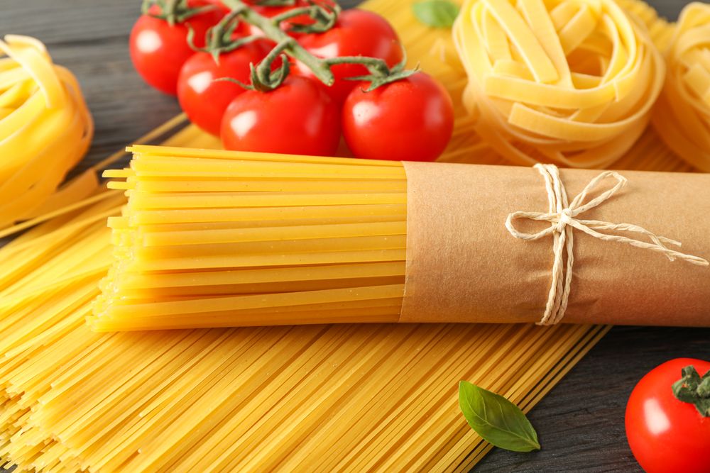 Composition with pasta, tomatoes and basil on wooden background, space for text and closeup