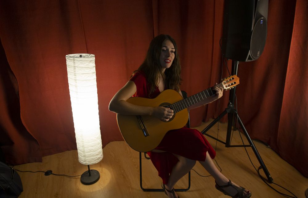 Creative woman singing and playing guitar on stage