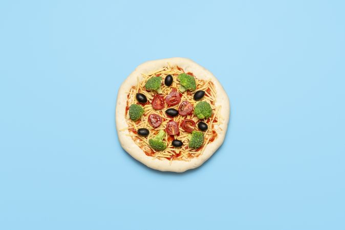 Vegetarian pizza uncooked on blue table