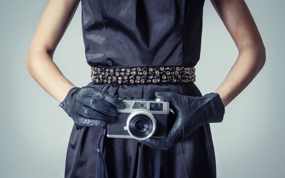 Model holding vintage camera in chic dress