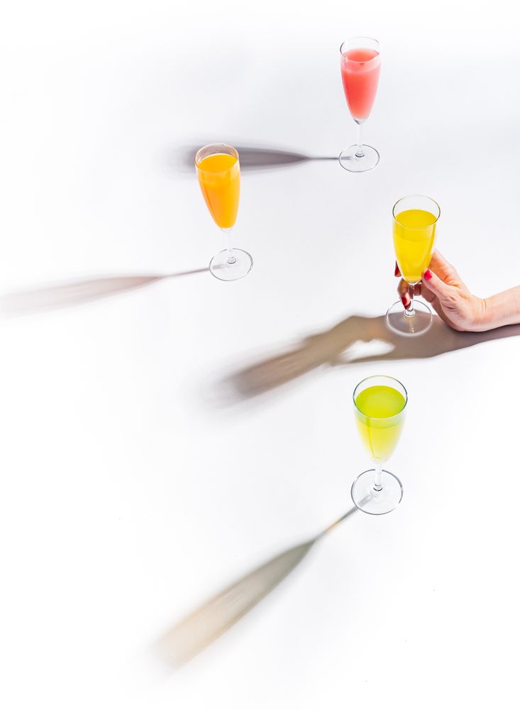 Hand and glasses of bright colorful drinks on table