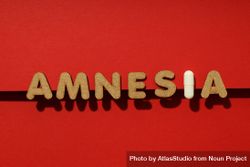 Cork letters of the word “Amnesia” with pill on red background in straight line 4NdKZ0