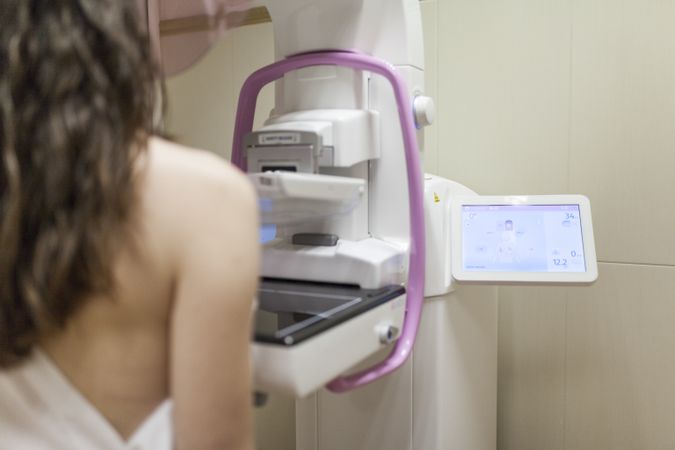 Female patient beside digital mammography unit