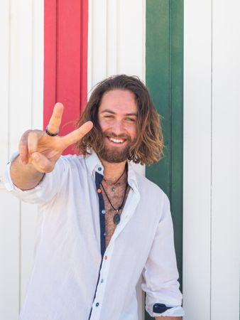 Cheerful guy standing near striped wall